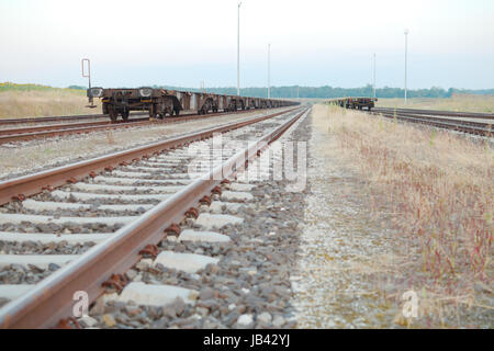 Railway Tracks with Empty Open Wagons Front in the Countryside Stock Photo