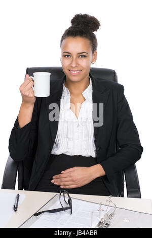Junge, hübsche Angestellte sitzt am Schreibtisch im Büro und hält eine Tasse Stock Photo
