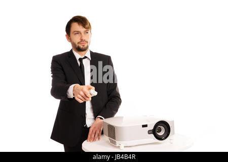 Businessman using a projector for a presentation or doing in house corporate training aiming the remote control as he changes the slide, isolated on white Stock Photo