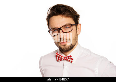 Old-fashioned nerdy businessman wearing a red and white polka dot bow tie looking over the top of his glasses , isolated on white Stock Photo