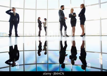 Several white collar workers communicating against window Stock Photo