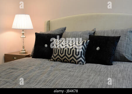 sylish bedroom interior design with black patterned pillows on bed and decorative table lamp. Stock Photo