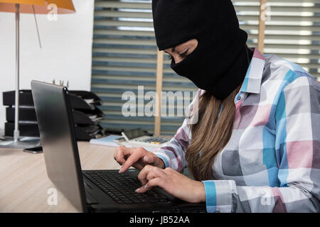 Focused hacker working on a computer, stealing data Stock Photo