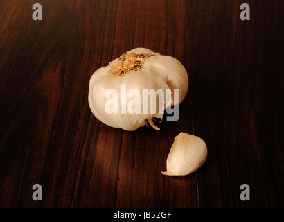 Garlic bulb with one loose clove on a dark wooden surface in landscape format with copy space Stock Photo