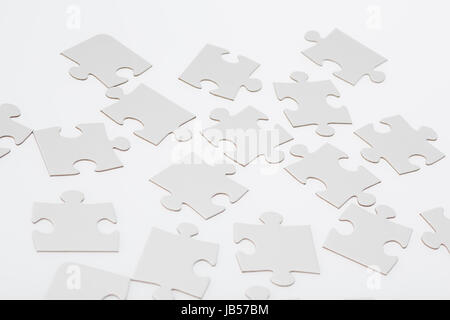 Blank jigsaw puzzle pieces on illuminated white background. Stock Photo