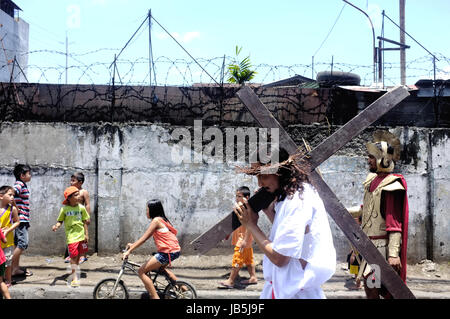 Cebu City, the Philippines - April 3, 2015. A person dressed as Jesus parade the street with his cross during easter celebrations in Cebu City. Stock Photo