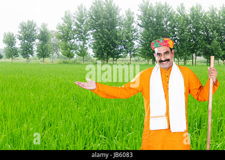 1 Indian Rural Rajasthani Farmer Standing In Farm and Gesturing hand Showing Crops.- Agriculture Concept Stock Photo