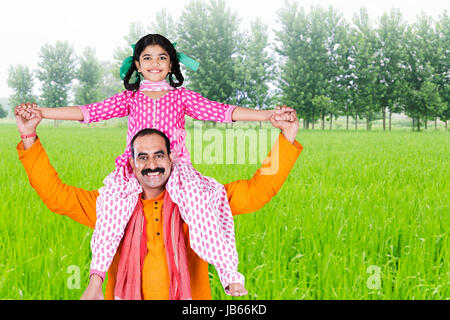 Portrait of happy Indian farmer carrying Little Daughter on shoulders at farm Stock Photo