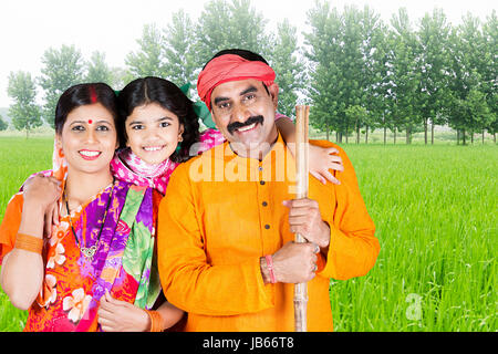 Happy Indian Rural Family- Parents And Little Daughter Standing Together In Field Enjoying Stock Photo