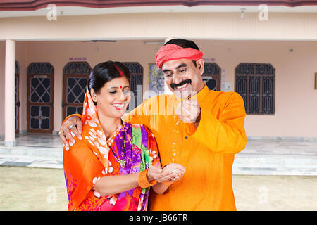 2 Indian Rural farmer Couple Holding wheat in his hand Falling Wheat Purity Quality in Village Behind House Stock Photo