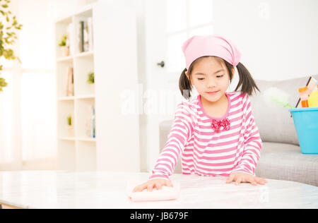 happy little asian chinese girl learning cleaning with rag in the living room at home. housework and household concept. Stock Photo