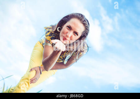 A woman bends over the camera and sends an air kiss Stock Photo