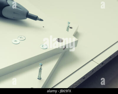 Close up of white furniture parts with cordless screwdriver, mounting furniture Stock Photo