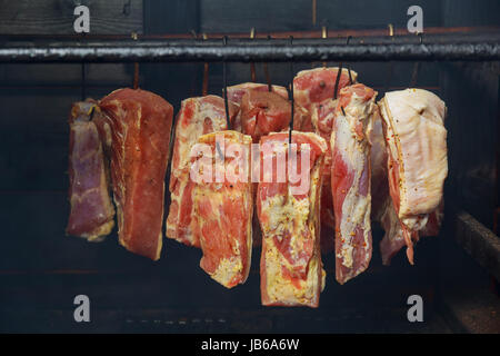 Hanging ham in the smokehouse smoked bacon for smoking Stock Photo