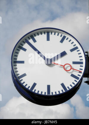 Nahaufnahme einer Bahnhofsuhr, im Freien, im Hintergrund blauer Himmel und weiße Wolken Closeup of a station clock, outdoor, in the background blue sky and white clouds Stock Photo