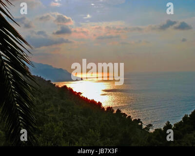 Sonnenuntergang am Mittelmeer, Blick über die Steilküste Mallorcas, im Vordergrund ein Palmenwedel Sunset at the Mediterranean, overlooking the steep coast of Mallorca, in the foreground a palm frond Stock Photo