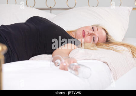 Naked drunk woman lying unconscious in bed after casual sex. Alcohol