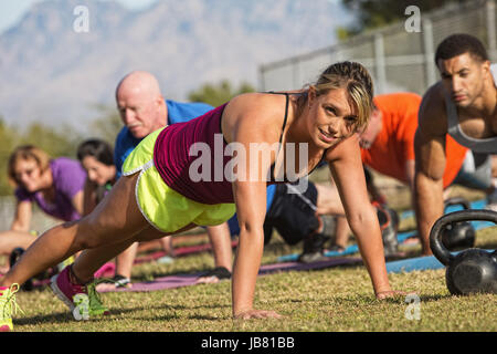Pretty European woman doing push-ups with group outdoors Stock Photo