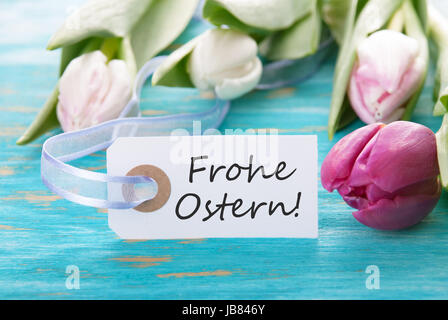 Tag with the german words Frohe Ostern which means Happy Easter and tulip on turquoise background Stock Photo