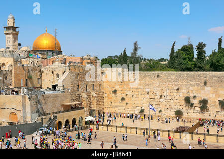 JERUSALEM - AUGUST 21: People at Western Wall (aka Wailing Wall) as Dome of the Rock mosque on background. These two religious sites are sacred and most important for jewish and muslims in Jerusalem, Israel on August 21, 2013. Stock Photo