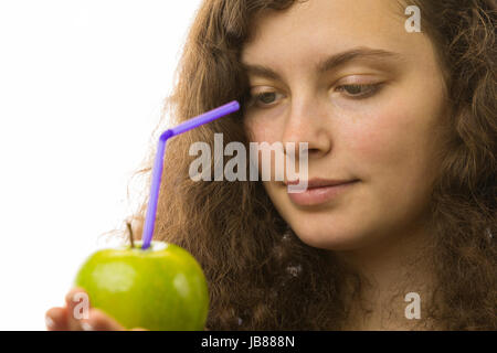 Eine junge hübsche Frau hält einen Apfel mit Strohhalm in der Hand Stock Photo