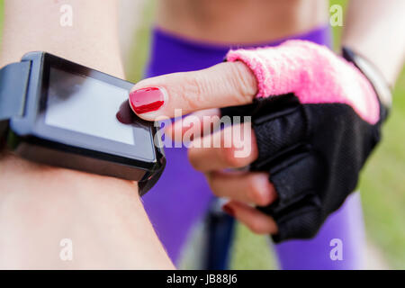 Woman riding a bike with a smartwatch heart rate monitor. Smart watch concept. Close-up smart watch on arm women to ride a bicycle. Woman is using sma Stock Photo