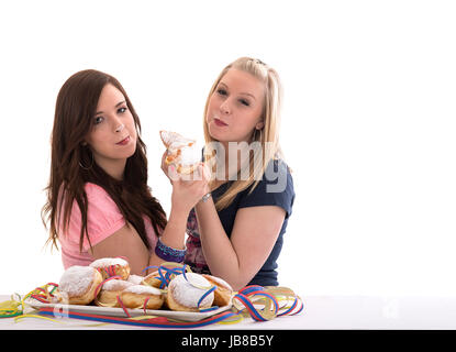 two girls eating carnival doughnuts on a prepared dish Stock Photo