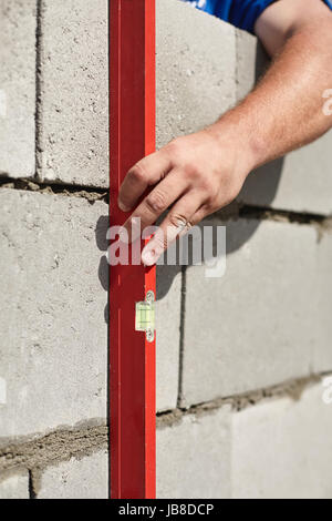 Mason checking plumb line of house wall being made from aerated concrete blocks Stock Photo