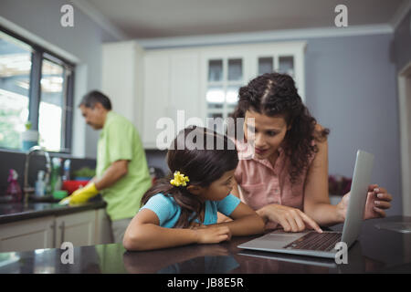 Mother and daughter using laptop in kitchen at home Stock Photo