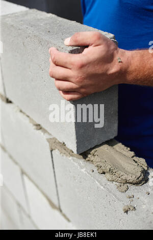 Close up of industrial bricklayer installing bricks on construction site Stock Photo