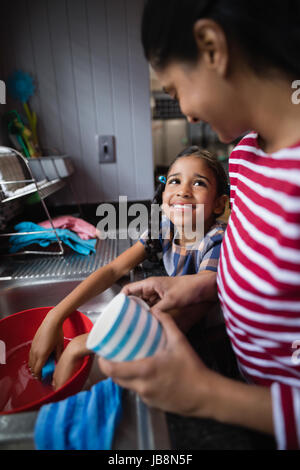 Cute smiling girl helping her mother in kitchen at home Stock Photo
