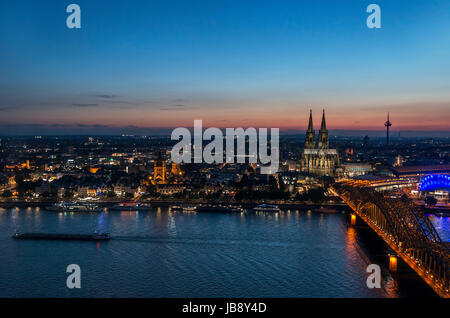 River Rhine at sunset, looking towards Cologne Cathedral and Old Town with Hohenzollern Bridge (Hohenzollernbrücke) in foreground, Cologne, Germany