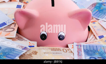 Unique pink ceramic piggy bank drowning in money, isolated on white Stock Photo