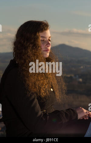 Eine junge hübsche Frau sitzt in der Wintersonne Stock Photo
