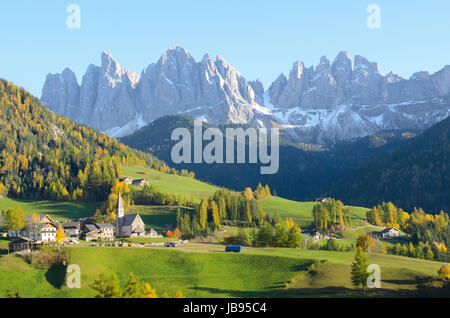 St. Magdalena with its characteristic church in front of the Geisler Dolomites mountain peaks in the Villnosstal in Italy in autumn. Stock Photo