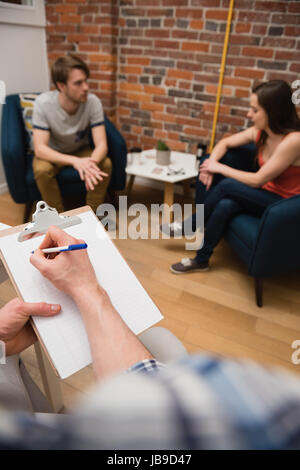 Hand of executive writing on clipboard in office Stock Photo