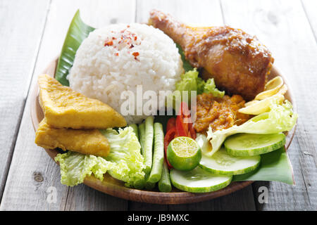 Famous traditional Indonesian food. Delicious nasi ayam penyet with sambal belacan.  Fresh hot with steam smoke. Stock Photo