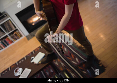 Man playing guitar in living room at home Stock Photo