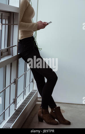 Low section of female executive using mobile phone in office Stock Photo