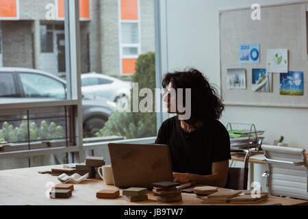 Thoughtful male executive working on laptop in office Stock Photo