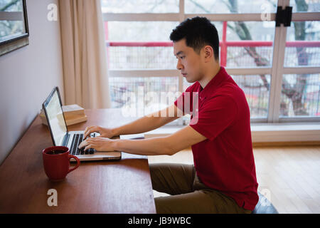 Man using laptop at desk in living room at home Stock Photo