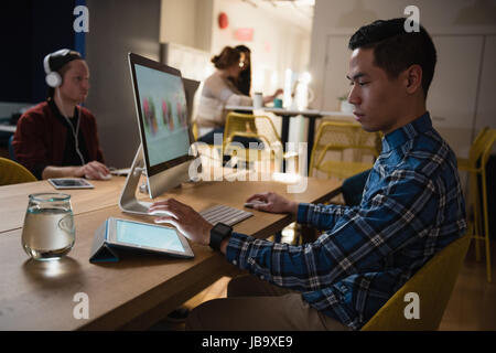 Attentive executive using digital tablet and computer in office Stock Photo