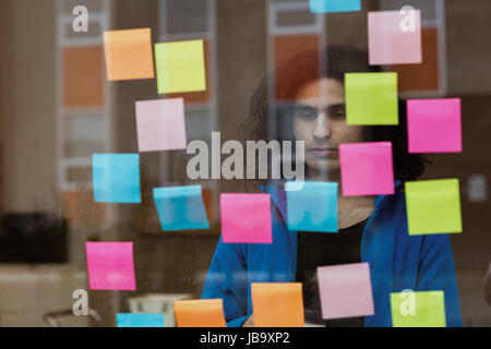 Thoughtful male executive looking at sticky notes in office Stock Photo