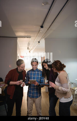 Executives discussing over digital tablet while having coffee in office Stock Photo