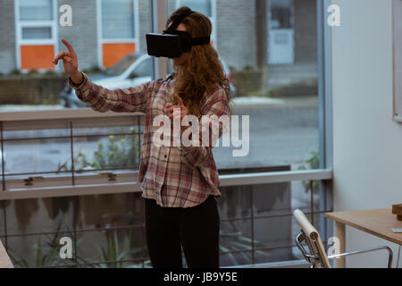 Female executive using virtual reality headset in office Stock Photo