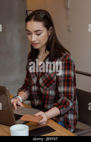 Female executive examining wooden slab while using laptop at desk in office Stock Photo