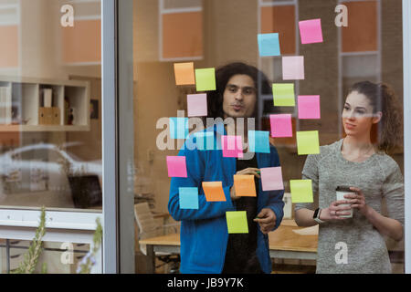 Business colleagues discussing over sticky notes in office Stock Photo