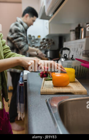 Mid section of woman cutting vegetables in kitchen at home Stock Photo