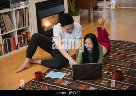 Happy couple using laptop near fireplace in living room at home Stock Photo