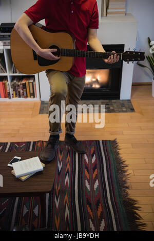 Man playing guitar in living room at home Stock Photo